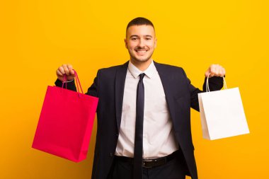 Genç ve yakışıklı iş adamı, arka planda alışveriş torbalarıyla.