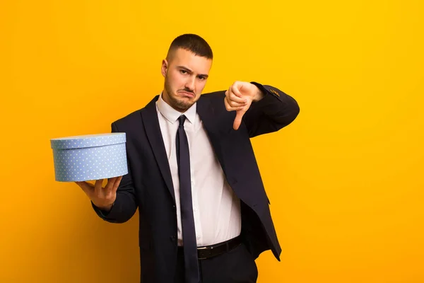 Jonge Knappe Zakenman Tegen Platte Achtergrond Met Een Geschenkdoos — Stockfoto