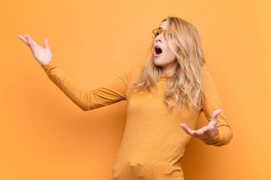 Genç, sarışın bir kadın opera icra ediyor ya da konserde şarkı söylüyor. Romantik, sanatsal ve tutkulu bir şekilde düz bir duvara yaslanıyor.