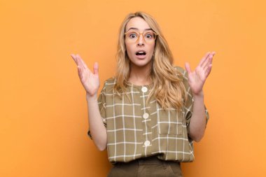 Genç ve güzel sarışın kadın şok olmuş ve şaşırmış görünüyordu. Düz renkli duvara karşı inanılmaz bir şey fark ettiğinde, ağzı açık kalmıştı.