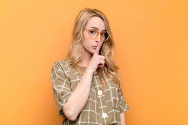 Genç, güzel, sarışın bir kadın sessizlik ve sessizlik istiyor. Parmağını ağzının önüne uzatıp 
