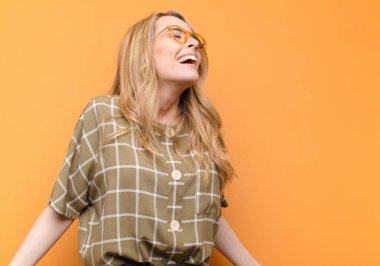 Genç, güzel sarışın kadın öfkeyle bağırıyor, agresif bir şekilde bağırıyor, gergin ve sinirli görünüyor.