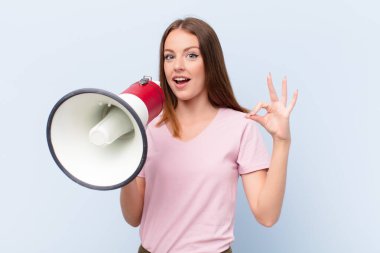 Genç kızıl saçlı kadın düz duvara karşı megafonla
