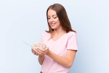 Genç kızıl saçlı kadın düz duvara karşı kahvaltı kasesiyle