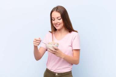 Genç kızıl saçlı kadın düz duvara karşı kahvaltı kasesiyle