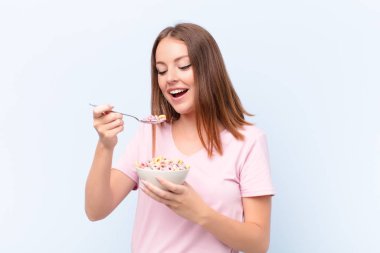 Genç kızıl saçlı kadın düz duvara karşı kahvaltı kasesiyle