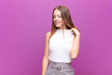 Genç kızıl saçlı kadın stresli, endişeli, yorgun ve hayal kırıklığına uğramış, gömleğini çekmiş, düz duvara karşı sorunlu görünüyor.