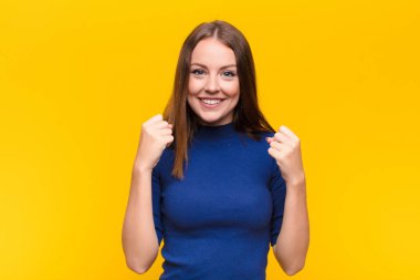 Genç kızıl saçlı kadın şok olmuş, heyecanlı ve mutlu hissediyor, gülüyor ve başarıyı kutluyor, vay canına! yassı duvara karşı