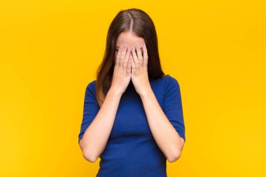 Genç kızıl saçlı kadın üzgün, hayal kırıklığına uğramış, gergin ve depresif, yüzünü iki eliyle kaplayan, yassı duvara karşı ağlayan