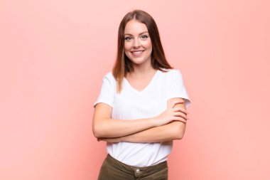 Genç kızıl saçlı kadın mutlu, gururlu ve tatmin olmuş görünüyor. Kolları düz duvara çarpmış başarılı bir şekilde gülümsüyor.