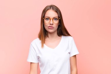 Genç kızıl saçlı kadın kafası karışık ve şüpheli hissediyor, merak ediyor ya da düz duvara karşı karar vermeye çalışıyor.