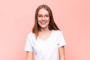 Genç kızıl saçlı kadın mutlu ve hoş bir şekilde şaşırmış görünüyor, düz duvara karşı büyüleyici ve şok olmuş bir ifadeyle heyecanlanıyor.