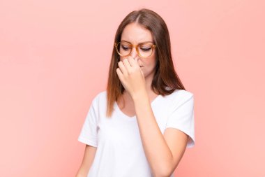 Genç kızıl saçlı kadın iğreniyor, burnundan pis ve tatsız bir kokuyu duvarda koklamaktan kaçınıyor.