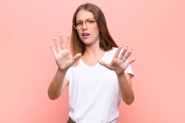 Genç kızıl saçlı kadın korku ve panik içinde geri çekilip çığlık atıyor düz duvara karşı bir kabusa tepki veriyor.