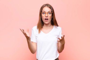 Genç kızıl saçlı kadın şok olmuş, şaşırmış, endişeli ve paniklemiş hissediyor. Stresli ve dehşete düşmüş bir şekilde düz duvara bakıyor.