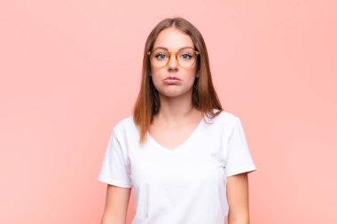 Genç kızıl saçlı kadın üzgün ve stresli. Kötü bir sürprizden dolayı üzgün. Olumsuz, endişeli bir bakışla düz duvara bakıyor.