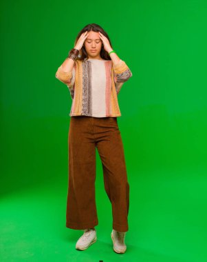 Genç ve güzel Latin kadın yoğun, düşünceli ve ilham verici görünüyor, beyin fırtınası yapıyor ve yeşil duvarın karşısında elleri alnında hayal ediyor.