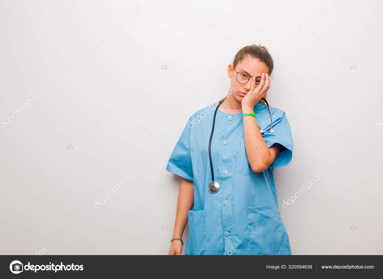 若いラテン語の看護師は退屈 フラストレーション 眠いと感じています疲れ 退屈な仕事の後 白い壁に手で顔を保持 ストック写真 C Kues