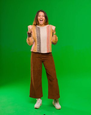 Genç ve güzel Latin kadın şok olmuş, heyecanlı ve mutlu hissediyor, gülüyor ve başarıyı kutluyor, vay canına! yeşil duvara yaslan