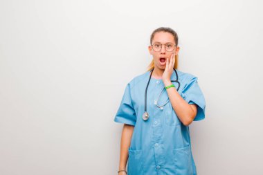 Genç Latin hemşire şok ve inançsızlıkla ağzı açık, elleri yanakları ve kolları çaprazlanmış, sersemlemiş ve beyaz duvara karşı şaşkına dönmüş hissediyordu.