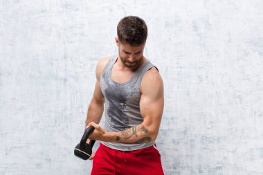 Dambıl spor konsepti olan düz renkli duvara karşı genç bir handosme.