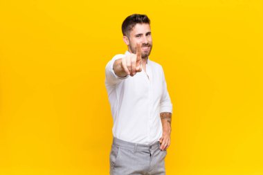 Genç Handosme gururla gülümsüyor ve gururla bir numaralı pozu veriyor. Düz renkli duvara karşı bir lider gibi hissediyor.