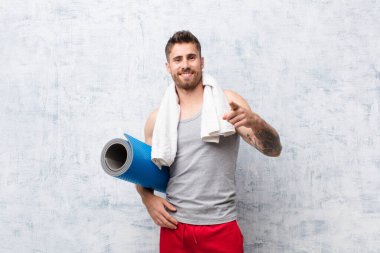 Genç adam yoga minderli düz renkli duvara karşı. spor konsepti