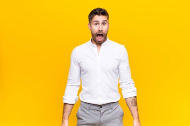 Genç adam şok olmuş ya da şaşırmış görünüyor, ağzı açık bir şekilde düz duvara karşı 