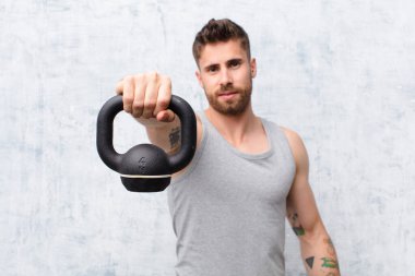 Dambıl spor konsepti olan düz renkli duvara karşı genç bir handosme.