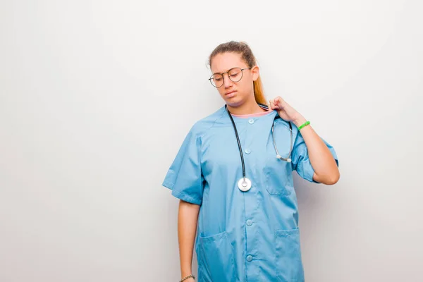 若いラテン語の看護師はストレスを感じ 不安を感じ 不満を感じ シャツの首を引っ張り 白い壁に対する問題に不満を感じ — ストック写真