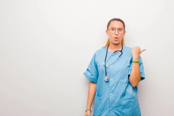 Junge Lateinische Krankenschwester Schaut Erstaunt Ungläubig Zeigt Auf Gegenstand Der — Stockfoto