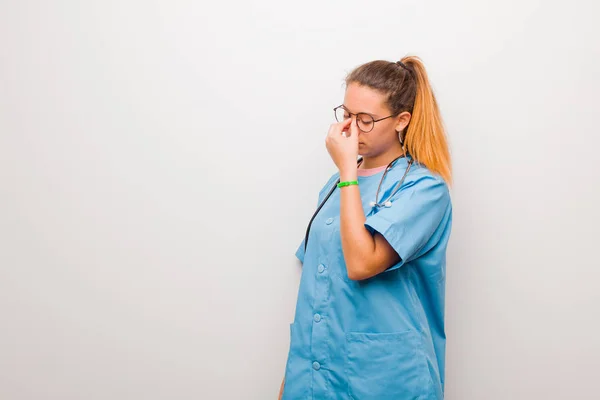 若いラテン語の看護師の感覚は強調しました 不幸と不満 白い壁に対する重度の頭痛の額と苦しみ片頭痛 — ストック写真