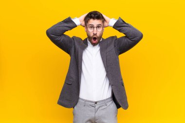 Genç adam heyecanlı ve şaşırmış görünüyor, iki eli başının üstünde ağzı açık, düz duvara karşı şanslı bir kazanan gibi hissediyor.