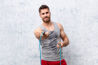 Genç handome adam düz renkli duvara karşı atlama halatıyla. spor konsepti