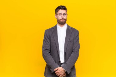 Genç adam merak ediyor, mutlu düşünceler ve fikirler düşünüyor, hayal kuruyor, düz renkli duvara karşı uzayı kopyalamaya çalışıyor.