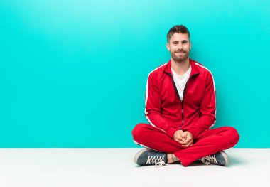 Genç handosme adam pozitif ve kendinden emin gülümsüyor, memnun görünüyor, arkadaş canlısı ve mutlu görünüyor düz renkli duvara karşı