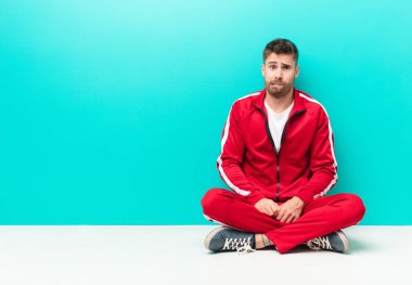 Genç Handosme erkeği hangi seçeneği seçeceği konusunda bilgisiz, kafası karışık ve kararsız hissediyor, düz renk duvarına karşı sorunu çözmeye çalışıyor