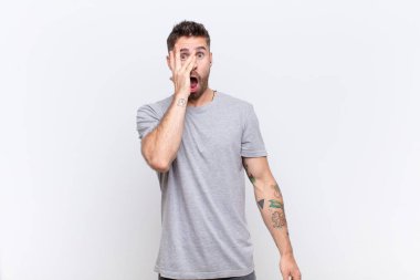 Genç adam şok olmuş, korkmuş ya da korkmuş görünüyor. Yüzü elle kaplanmış ve parmaklarının arasından düz duvara bakıyor.