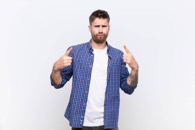 Kötü tavırlı genç adam gururlu ve agresif görünüyor, yukarı bakıyor ya da duvarlara yaslanmış ellerle dalga geçiyor.