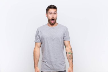 Genç adam şok olmuş ya da şaşırmış görünüyor, ağzı açık bir şekilde düz duvara karşı 