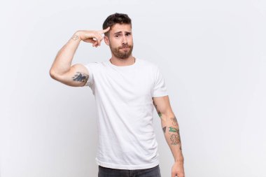 Genç adam kafası karışık ve şaşkın hissediyor. Deli, deli ya da düz renkli duvara karşı aklını kaçırmış olduğunu gösteriyor.