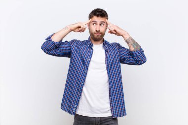 Genç adam konsantre olmuş ve bir fikir üzerinde kafa yoruyor, düz renk duvarlara karşı bir meydan okuma veya soruna çözüm hayal ediyor.