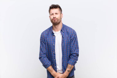 Genç adam dudaklarını birbirine bastırıyor, tatlı, eğlenceli, mutlu, sevimli bir yüz ifadesiyle, düz renkli duvara öpücük yolluyor.