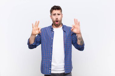 Genç adam şok olmuş, şaşırmış ve şaşırmış hissediyor. Onaylıyor, iki eliyle düz duvara işaret veriyor.