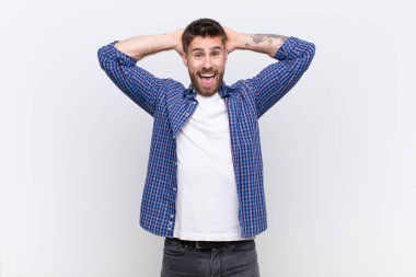 Genç adam mutlu, kaygısız, arkadaş canlısı ve rahat görünüyor hayattan ve başarıdan keyif alıyor, düz renkli duvara karşı pozitif bir tutum sergiliyor. 