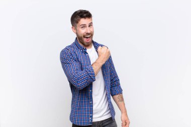 Genç handome erkeği mutlu, pozitif ve başarılı hissediyor, bir meydan okumayla karşılaştığında motive oluyor veya düz renkli duvara karşı iyi sonuçlar alıyor