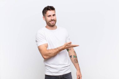 Genç adam neşeyle gülümsüyor, mutlu hissediyor ve fotokopi uzayında bir konsept gösteriyor.