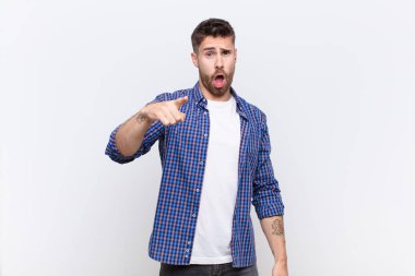 Genç bir adam, kızgın agresif bir ifadeyle kameraya bakıyor. Düz duvara karşı öfkeli, çılgın bir patron gibi görünüyor.