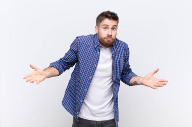 Genç handome 'un kafası karışmış ve kafası karışmış, hiçbir fikri yok, düz renkli duvara bakan aptal ya da aptal bir bakışla tamamen kafası karışmış.