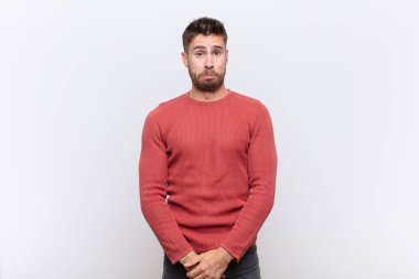 Genç adam üzgün ve stresli hissediyor. Kötü bir sürpriz yüzünden üzgün. Renk duvarına karşı olumsuz ve endişeli bir bakış atıyor.